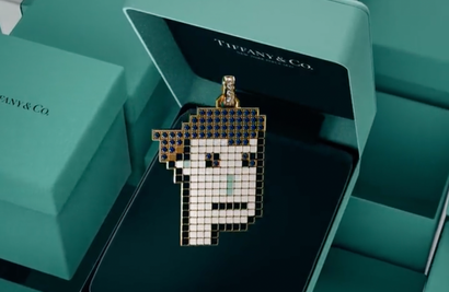 A pixelated face pendant made of precious metals and gems