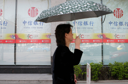 A woman holding an umbrella walks past a China Citic Bank, a subsidiary of Citic Group, in Wuhan, Hubei province March 27, 2014.