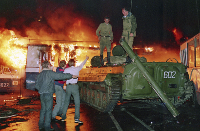 A trolley bus that was used by anti-coup demonstrators to block the exit of Soviet armored personnel carriers from the area near the Soviet Foreign Ministry office burns during a verbal confrontation between some demonstrators and Soviet soldiers standing atop an armored vehicle in downtown Moscow, Soviet Union