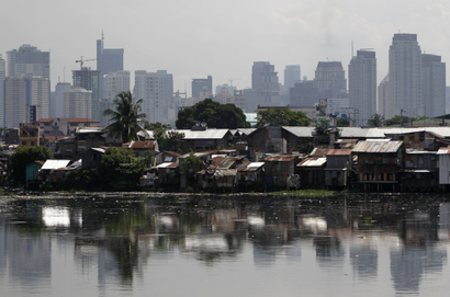 High-rise buildings are seen in the background with slum dwellings in the front, near a polluted river in Manila May 31, 2013. The Philippines.