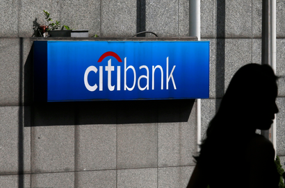 A woman walks past a Citibank logo