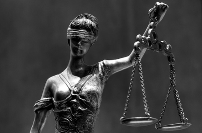 A sculpture of lady blind justice stands with her eyes blindfolded and a scale in her hand.