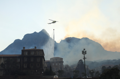 A helicopter drops water as the library at the University of Cape Town burns after a bushfire broke out on the slopes of Table Mountain in Cape Town on April 18.