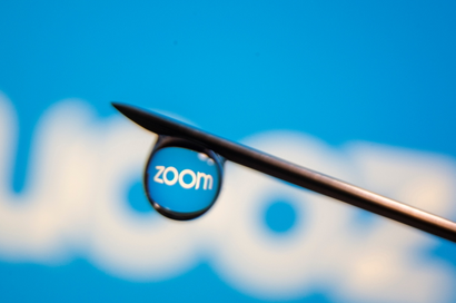 The Zoom logo is reflected in a drop on a syringe needle