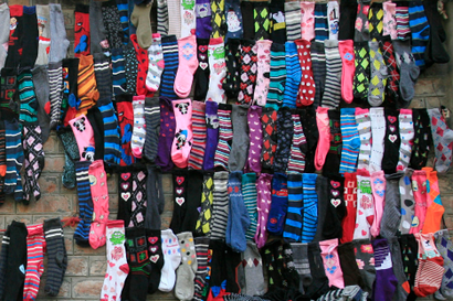 Dozens of brightly colored socks are hung up at a small shop.
