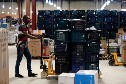 A man pushes a cart loaded with crates