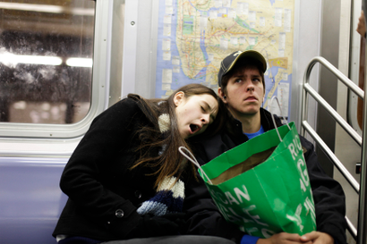 A woman yawns as she leans on her boyfriend while riding the subway