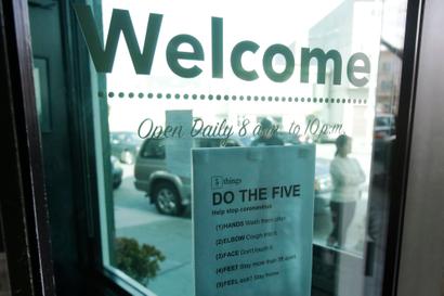 A sign about preventing the spread of the coronavirus is posted on the door of The Green Cross cannabis dispensary in San Francisco, Wednesday, March 18, 2020. As about 7 million people in the San Francisco Bay Area are under shelter-in-place orders, only allowed to leave their homes for crucial needs in an attempt to slow virus spread, marijuana stores remain open and are being considered "essential services."