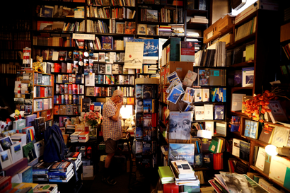 A man looks at a shelf in a store crammed with books