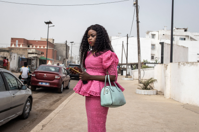 A Senegalese lady standing by the roadside holding her phone