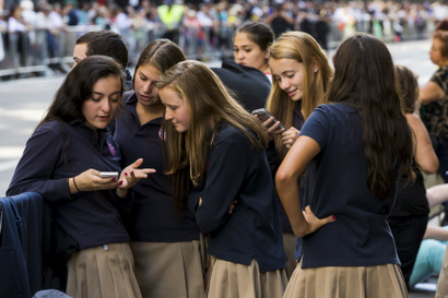 A group of Catholic school girls look at their phones as they wait on the route that Pope Francis will take later in the day near St. Patricks Cathedral in New York September 24, 2015. REUTERS/Lucas Jackson - GF10000219774