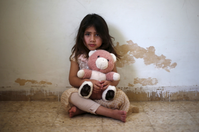 Asmaa, the daughter of Abdul Rahaman al-Sarhan, a blind Syrian refugee, poses with her toy as she plays in her family home in the city of Zarqa, Jordan, June 18, 2015. Sarhan and his family of seven fled from their home in Damascus to Jordan about two and a half years ago. After the World Food Program reduced their humanitarian aid vouchers, Sarhan's sons, Jaber, 15, and Mohammad, 13, had to leave school in Zarqa in Jordan, to find jobs to help feed the family.