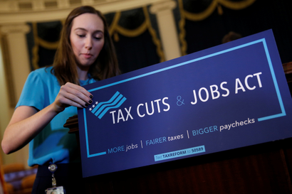 A congressional aide places a placard on a podium for the House Republican's legislation to overhaul the tax code on Capitol Hill in Washington