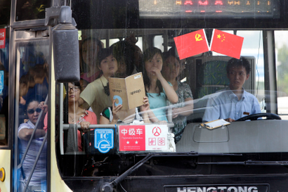 Passengers stand in a crowded bus decorated with Chinese national and communist party flags to celebrate the upcoming 90th anniversary of the founding of the Communist Party of China (CPC) in Chongqing municipality June 30, 2011
