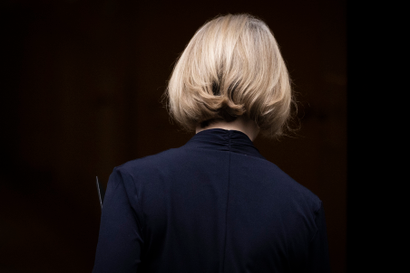 A photo framing the back of Liz Truss's head. Her hair is styled in a short, blonde bob and she's wearing a dark navy top.