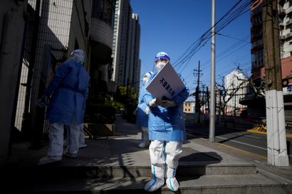 A person wearing protective gear holds a sign.