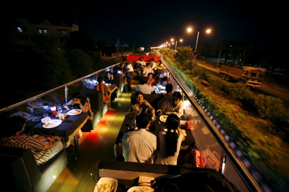 People dine on a double-decker bus which has been converted to a mobile restaurant as it travels through the streets of Ahmedabad