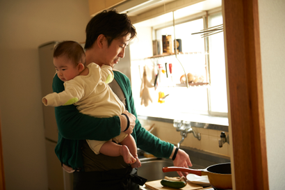 Father cooking and holding his baby in the kitchen