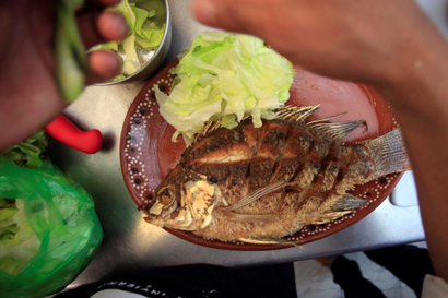A man prepares a plate of Mojarra fish, also known as Gerreidae, at a seafood restaurant in Monterrey, Mexico