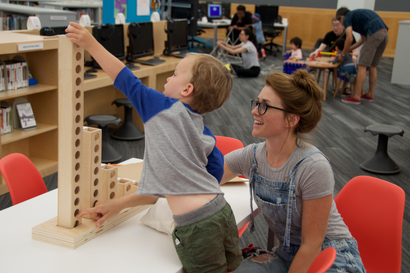 A young boy and his mom play with Learning Beautiful's binary towers at the Chicago Public Library.
