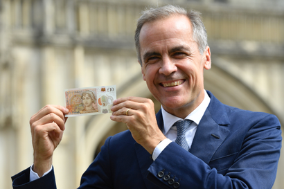 Mark Carney of the Bank of England holds up a banknote