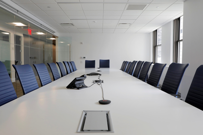 Blue chairs are arranged around a white conference table at a boardroom in Manhatthan.