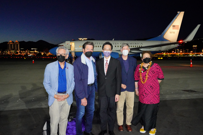 US lawmakers stand in front of a plane in Taiwan. It's nighttime in the photo.