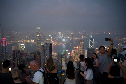 In this Oct. 9, 2019 photo, tourists take photos in a foggy evening at the Victoria Peak in Hong Kong.