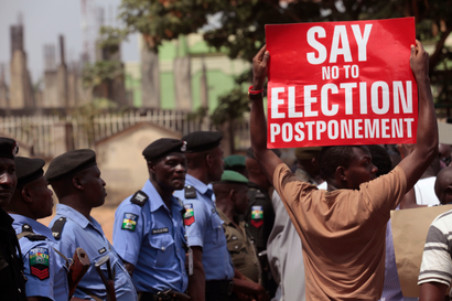 a protestor holds a banner as Nigerian security forces look on