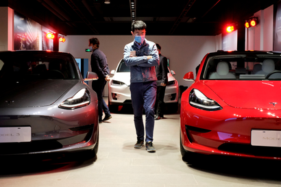 a man walks between two Tesla vehicles in the company's Shanghai showroom.