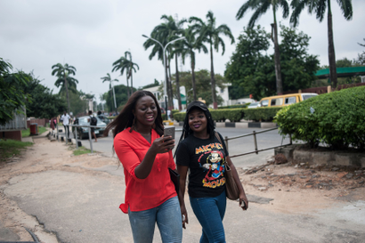 Two African women walking and looking at a phone screen