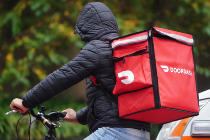 A delivery worker wearing a DoorDash backpack while on bike