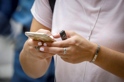 A woman holds a Juul e-cigarette as she uses her phone in New York City, U.S., September 13, 2018.