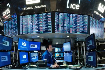 A trader works on the floor of the New York Stock Exchange (NYSE) surrounded by monitors showing stock ticker symbols..