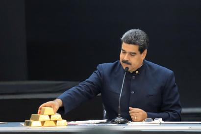 Venezuela's President Nicolas Maduro touches a gold bar as he speaks during a meeting with the ministers responsible for the economic sector at Miraflores Palace in Caracas.