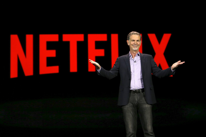 Netflix co-founder and co-CEO Reed Hastings in front of a Netflix logo