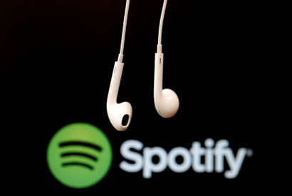 Headphones are seen in front of a logo of online music streaming service Spotify