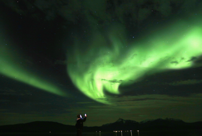 A tourist takes photos of an Aurora Borealis