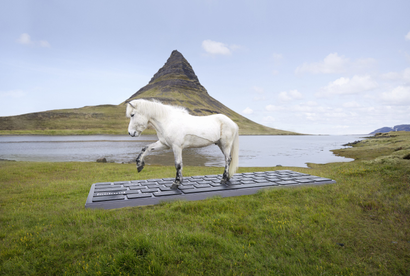 a white horse types on a giant keyboard with its hooves in front of a mountain