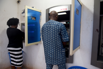 A woman and a man using two separate ATMs 