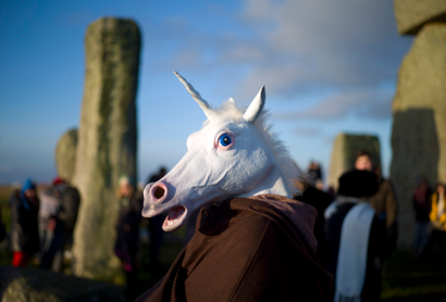 A reveller, dressed as a unicorn, celebrates the sunrise during the winter solstice at Stonehenge on Salisbury Plain in southern England