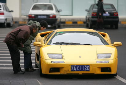 A couple get a close-up look at a Lamborghini Diablo VT parked in Beijing Thursday, Dec. 16, 2004. Two decades of economic reforms in China have resulted in riches for some, but at least 29 million people still live below poverty levels, according to government figures.