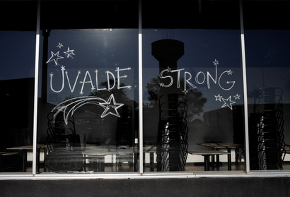 An image of a glass storefront with the words "Uvalde strong" written in white marker, all caps. Surrounding the words are drawings of stars.