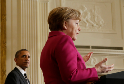 Barack Obama watches Angela Merkel speak at the White House.