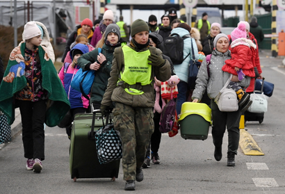 A member of the Polish Territorial Defence Force carries luggage as people coming from Ukraine,