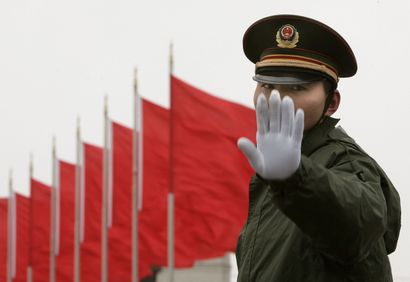 A soldier gestures to the photographer as he stands guard at the Tiananmen Square in Beijing March 4, 2007. China's will boost defence spending by 17.8 percent in 2007, accelerating the emerging power's string of annual double-digit rises in money for a modern military that reflects its economic strength. REUTERS/Joe Cha