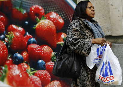 A woman carries a Tesco shopping bag outside a branch of the supermarket in London.