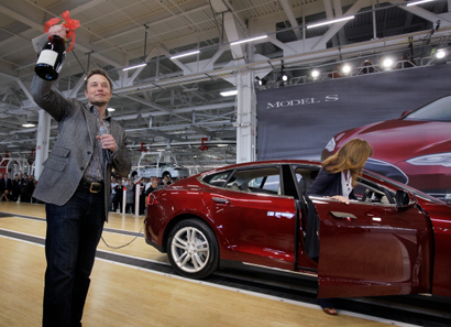 In this June 22, 2012 file photo, Tesla Motors Inc. CEO Elon Musk holds up a bottle of wine given as a gift from one of their first customers, right, during a rally at the Tesla factory in Fremont, Calif. Tesla Motors Inc. on Wednesday, July 25, 2012 said that its second-quarter net loss nearly doubled as it invested heavily to launch its second vehicle, the Model S. (AP Photo/Paul Sakuma, File)