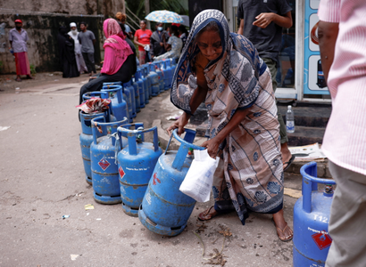 A woman moves a gas tank as she stands in line to buy another tank near a distributor, amid the country's economic crisis, in Colombo, Sri Lanka.