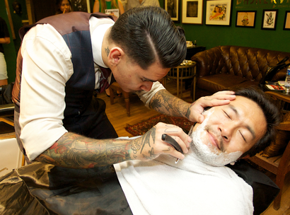 A barber shaves a man's beard, leaving his mustache